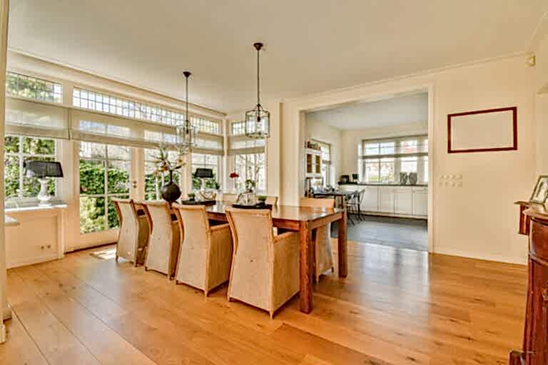 a dining room with wood flooring and large windows that look out onto the garden outside, as well in this photo
