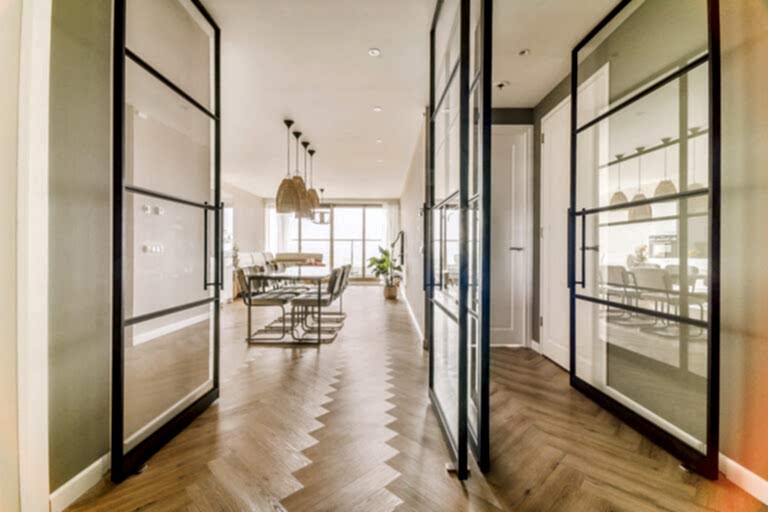 Corridor of contemporary apartment with opened doorway leading to living room